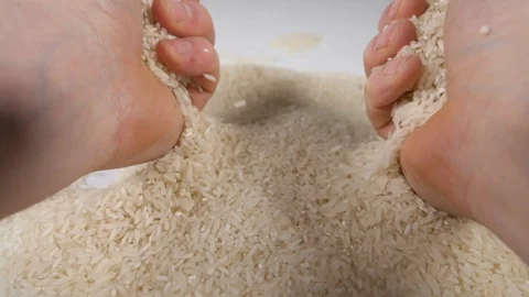 Slow motion white rice with mans hands grabbing and pouring onto a pile of rice. Stock Footage 88344806