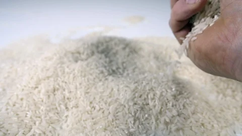Slow motion white rice poured with mans hand onto a white surface,  uncooked  Stock Footage 88344028