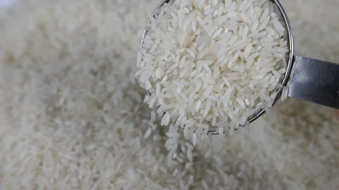 Slow motion white rice with a stainless steel measuring portion utensil. Stock Footage 88344357
