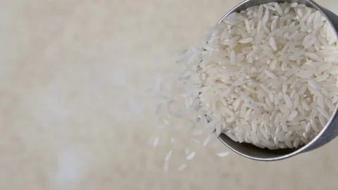 Slow motion white rice with stainless steel measuring utensil, mans hand pouring Stock Footage 88518818