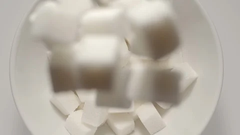 SLOW MOTION: White sugar cubes falling into a bowl bowl Stock Footage 108573469