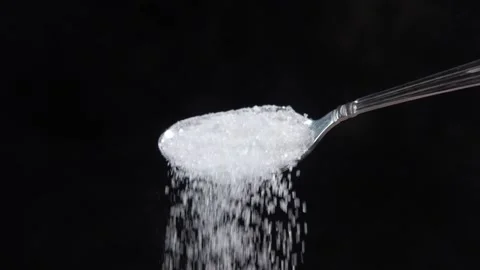 Slow motion of white sugar pouring from a spoon isolated on black Stock Footage 149255360