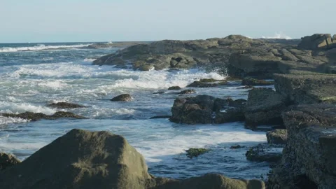 Slow motion white water hitting rocky shore line Видео 297718790