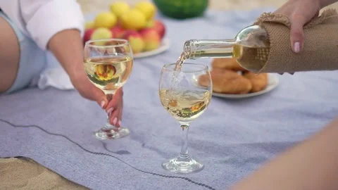 Slow motion white wine pouring into wine glass at picnic tablecloth close up Video stock 253173211