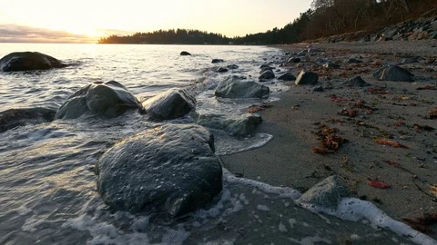 Slow motion wide angle sunrise beach shot with waves and rocks in foreground Stock Footage 128408574