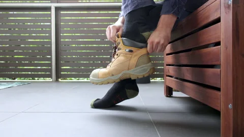 Slow motion wide of construction worker putting on their work boots before work Stock Footage 239969350
