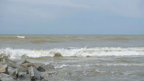 A slow-motion wide shot of waves crashing onto the rocks at the beach Stock Footage 231761257