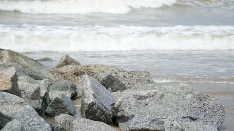 A slow-motion wide shot of waves crashing onto the rocks at the beach Video stock 231761887
