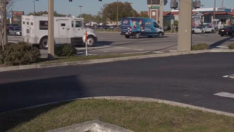 Slow Motion wide view a white Lomis armored car going straight and a white van Stock Footage 263921979