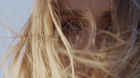 Slow motion the wind flutters the young woman's blond hair against the blue sky Stock Footage 128951222