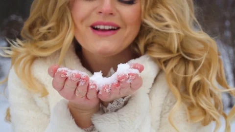 Slow motion of winter blond lady blowing a handful of snow right in the camera Stock Footage 83020859