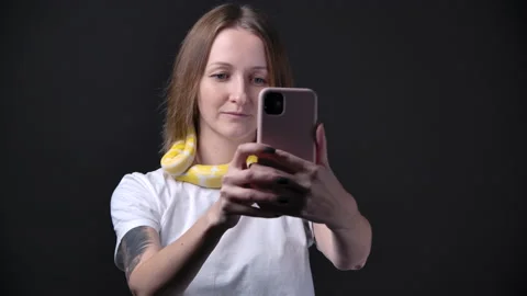 Slow motion of woman with albino python, holding smartphone 動画素材 143992130