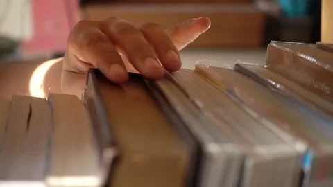 Slow motion of woman hand finding a book on bookshelf in the library Stockbeeldmateriaal 76996461