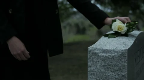 Slow motion woman placing rose on top of grave stone in cemetary Stock Footage