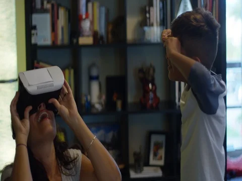 Slow Motion of woman playing with a VR headset while her son watches Stock Footage 78490983