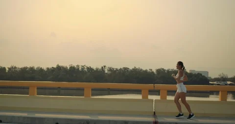 SLOW MOTION, Woman Running marathon riverside street summer sunset Stockbeeldmateriaal 124374953