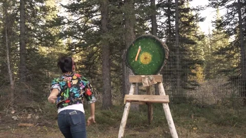 Slow motion of woman throwing axe at target in adventure park in forest Stock Footage 201939928