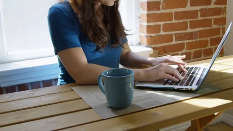 Slow motion of woman using her laptop and having a cup of coffee in the morning Stock Footage 86779785
