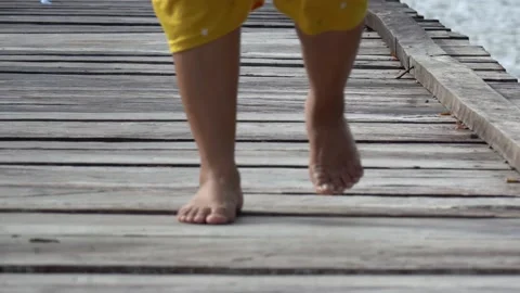 Slow motion of a woman walking barefoot on a wooden bridge Stock Footage 230163053