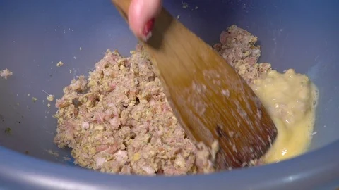 Slow motion – Woman’s hand mixing whisked egg into a bowl of stuffing mix. Stock Footage 100284041