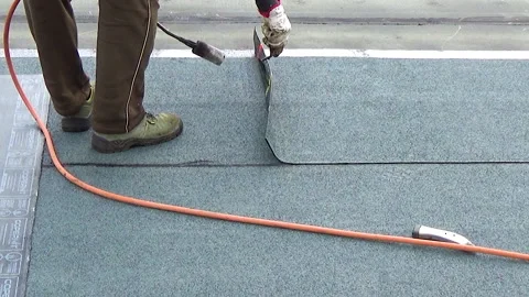 Slow motion. Worker preparing part of bitumen roofing felt roll for melting b 動画素材 130585553