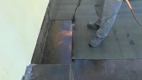 Slow motion. Worker preparing part of bitumen roofing felt roll for melting b Stock-Footage 154402879