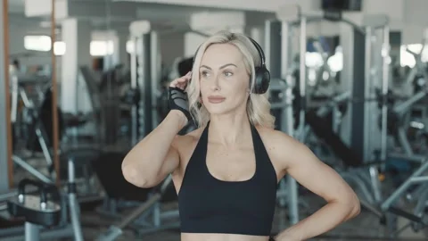 Slow motion workout with focused girl wearing headphones at a modern gym Stock-Footage 302117112