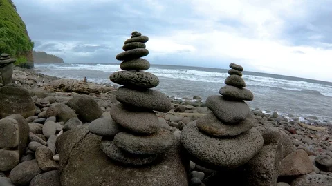 Slow motion wrap around two cairns on stony beach at Pololū Valley Hawaii 4K Stock Footage 98425901