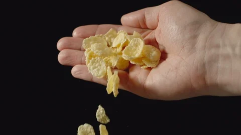 SLOW MOTION: Yellow cornflakes fall from man's palm - Front view Vídeo Stock 102212704