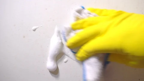 Slow motion: Yellow gloved hand cleaning a white painted door. Video stock 102831391