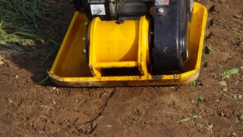 Slow motion yellow vibratory plate smoothing brown soil. Stock Footage 95639657