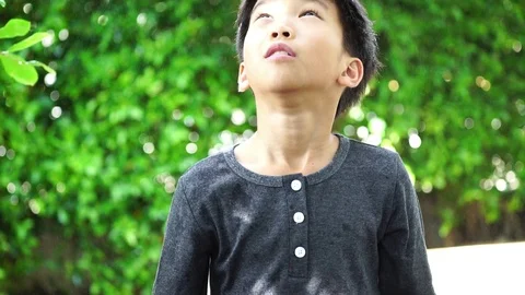 Slow motion young Asian boy use umbrella to protect rain shower Stock Footage 92249451