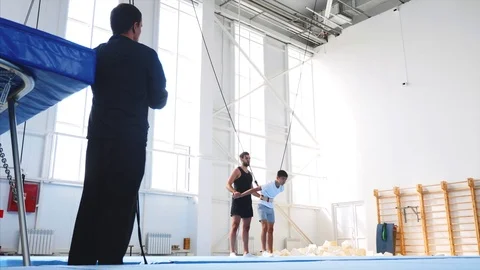 A slow motion of a young athlete doing an air back flip on safety slings Stock Footage 117470441