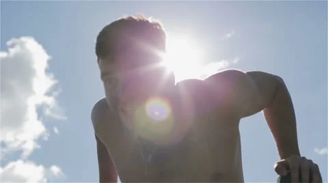 Slow motion. Young athlete pushing up at the parallel bars in sun glare. Stock Footage 68530804