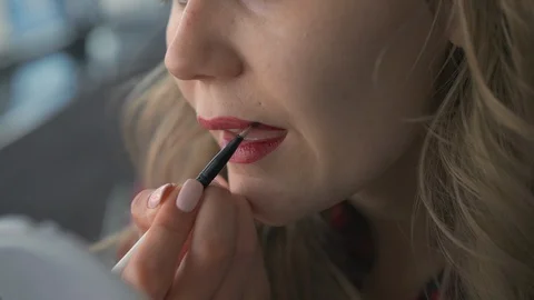 Slow Motion A young beautiful unrecognized girl applies lipstick to her lips Video stock 105031863