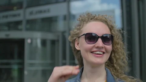 Slow motion of young blonde putting on her sunglasses, walking outdoors Stock Footage 143012659