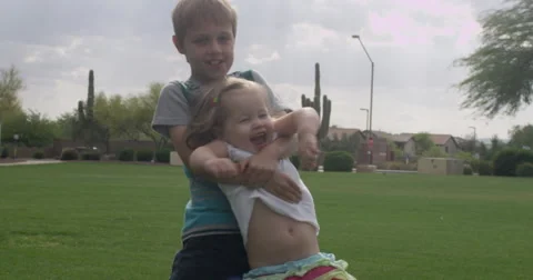 Slow Motion Young Boy and Toddler Girl Spin in Park Stock Footage 61521272