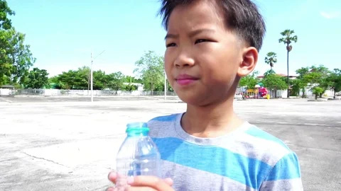 Slow motion young boy drink water from a bottle and drop in a bin Stock Footage 90507819