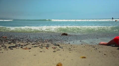 Slow motion of young boy lying by ocean playing with sand Stock Footage 63887680