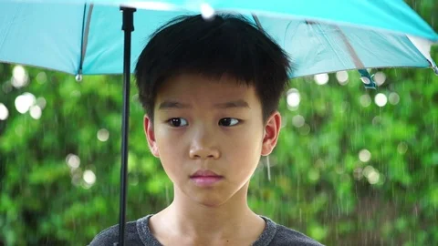 Slow motion Young boy play with rain drop under an umbrella. Stock Footage 93942939