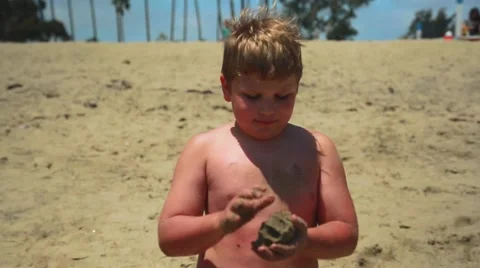 Slow motion of young boy standing at beach playing with sand Stock Footage 63886821