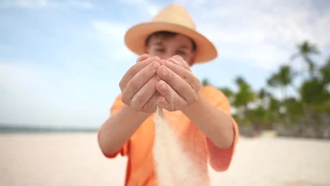 Slow motion of young boy in straw hat scatter the sand from the hands on the Stock Footage 279128016