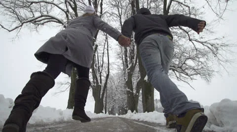 SLOW MOTION: Young couple running through winter promenade Stock Footage 22556039