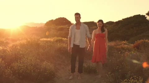 Slow motion of young couple walking on sand dunes in sunset. Stock Footage 43663976