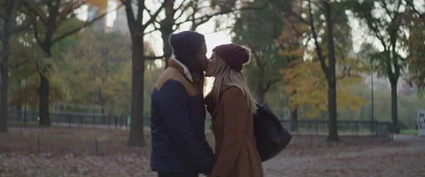 Slow motion of young couple in winter clothes holding hands and kissing in park Stock Footage 208735621
