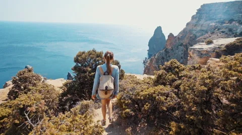 Slow motion of a young female walking a trail on the seashore clif Stock Footage 67102403