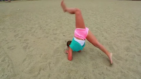 Slow motion of young girl practicing gymnastics on the sand at beach Stock Footage 63748950