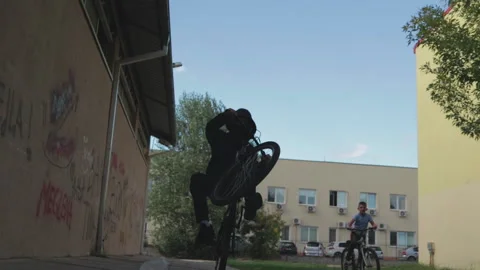 Slow motion of a young man doing a "wheely" on his bicycle Stock Footage 147201436