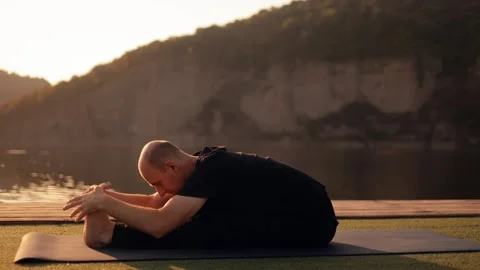 Slow motion of a young man meditating on the riverbank outdoors in the morning Stock Footage 246559269