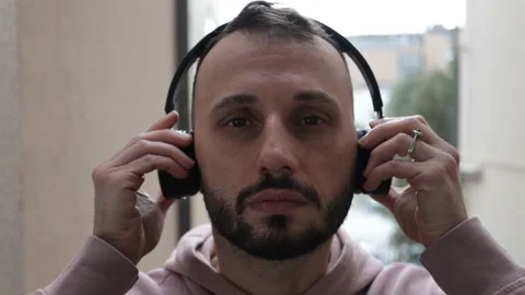 Slow motion of young man putting on headphones looking at the camera. Stock Footage 170962684